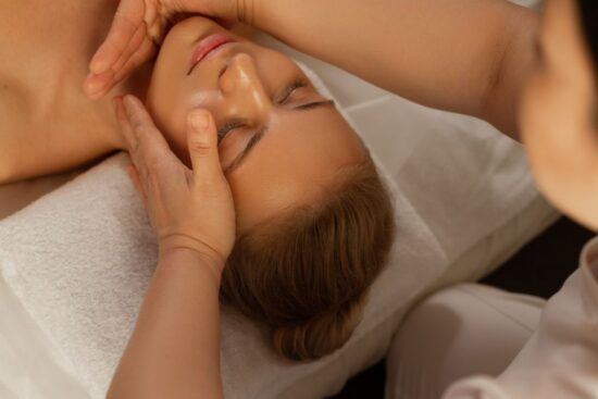 os poderes de cura da massagem terapêutica - na imagem a modelo recebe uma massagem na face de uma massoterapeuta profissional.