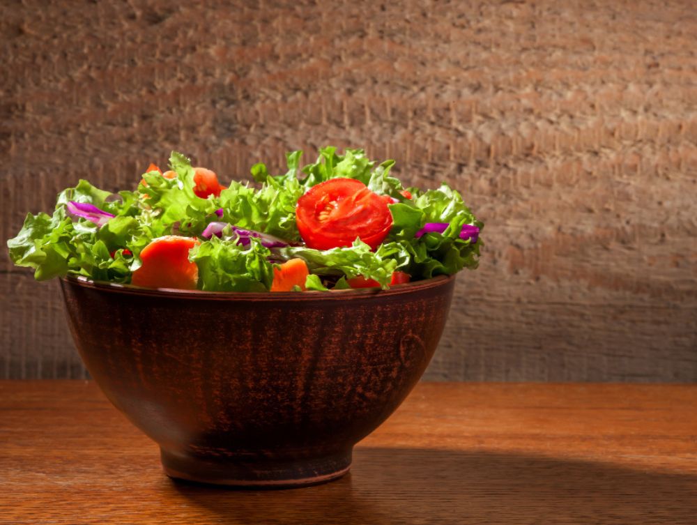 Alimentação saudável: a imagem mostra uma bacia de salada com alface, repolho roxo e tomates cortados.